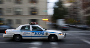 NYPD squad car speeds down the street.